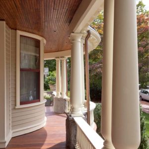 This porch is supported by tall, white, classical-style columns with decorative capitals. Beautiful!